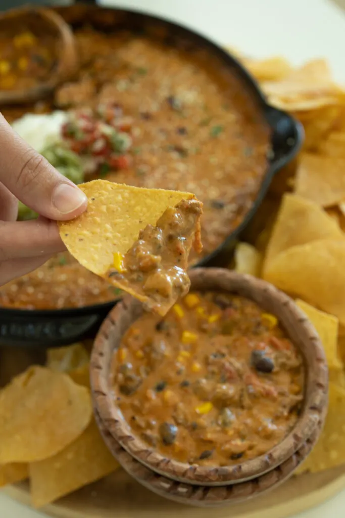 dipping a chip in taco dip with ground beef