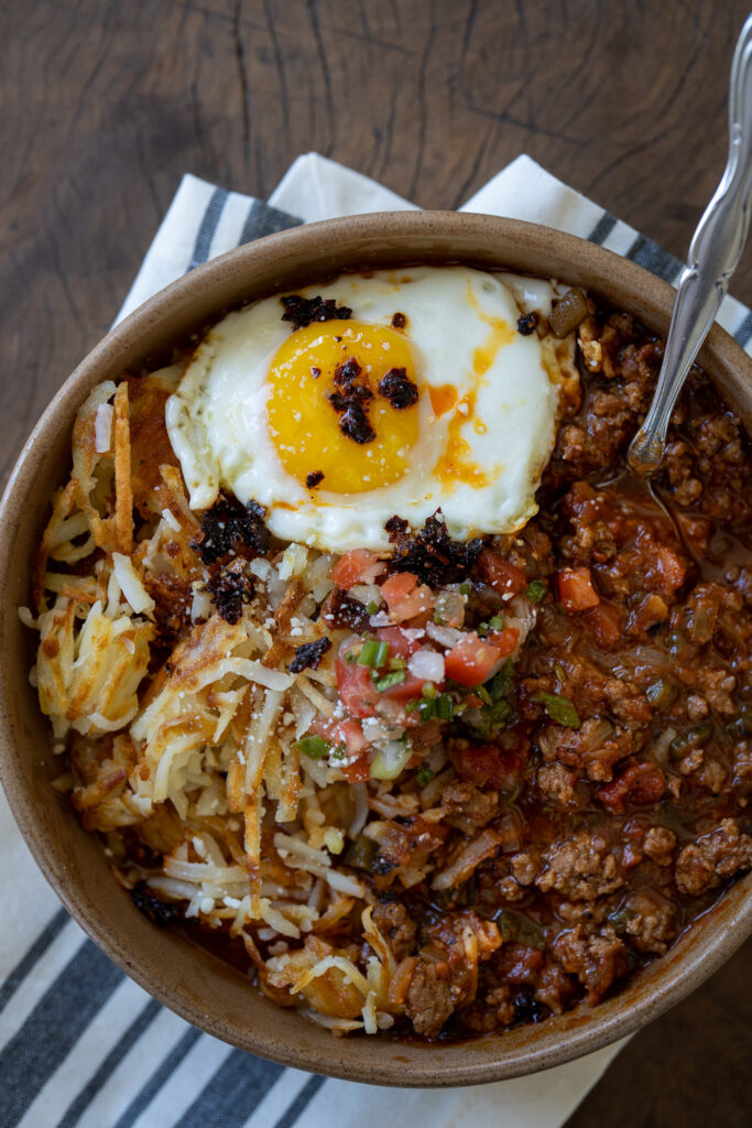 bowl of breakfast chili and eggs over hash browns