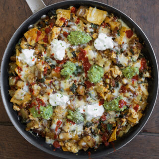 breakfast enchilada skillet topped with fat free Greek yogurt, guacamole, cotija cheese, and hot sauce