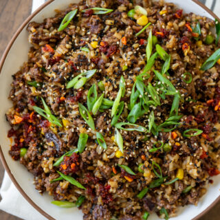ground beef fried rice in a bowl garnished with sliced scallions