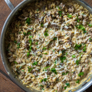 sauté pan with ground turkey and mushroom orzo garnished with parsley and grated cheese