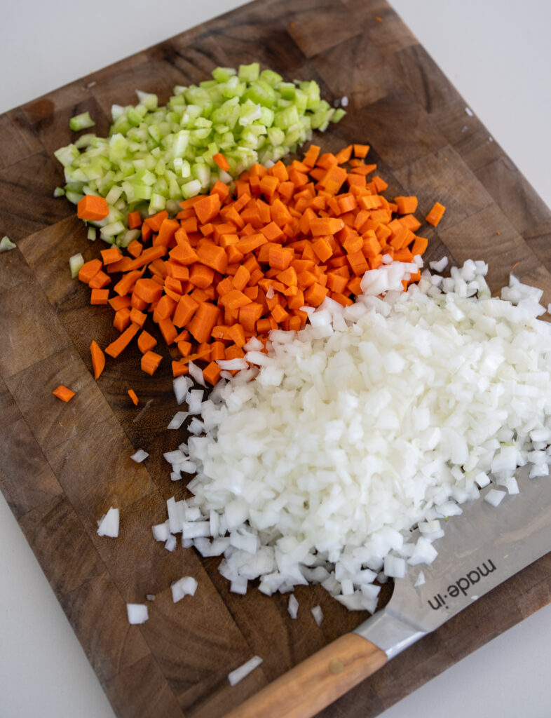 diced onion, carrots, and celery on a cutting board