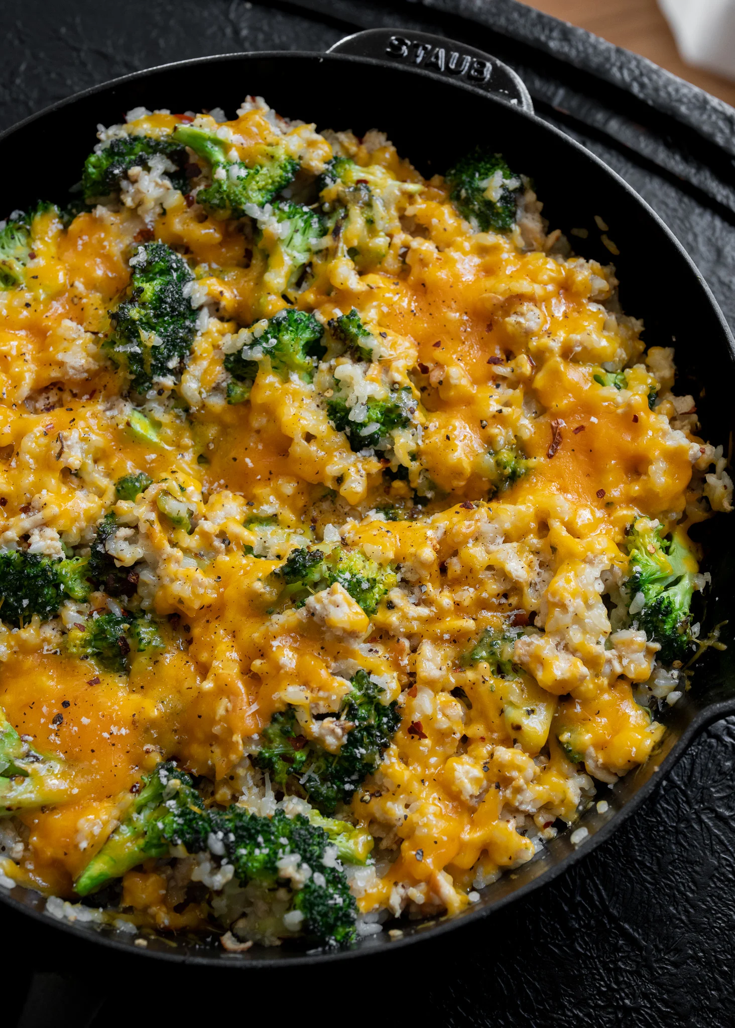 cheesy broccoli with ground chicken and rice in a cast iron skillet
